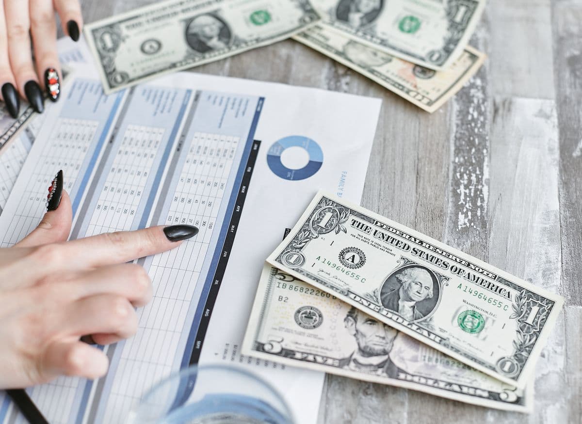 Hands reviewing a financial document with cash on a table