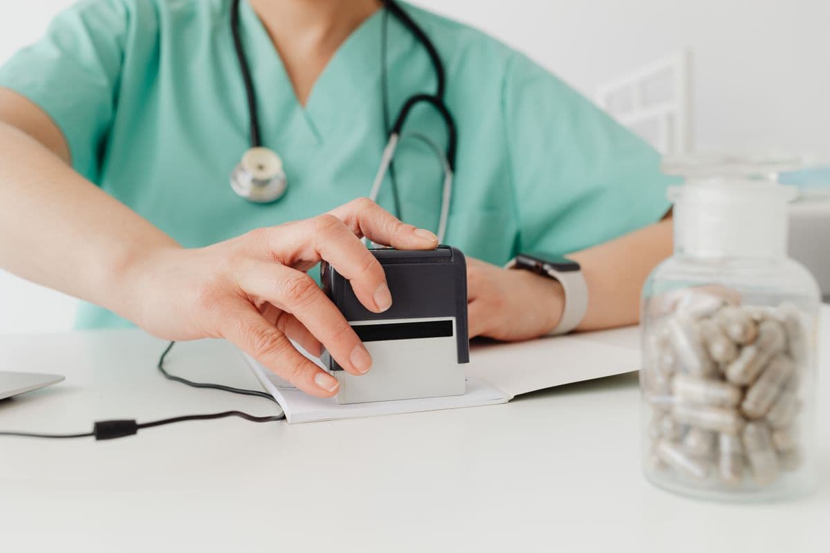 Close-up of a doctor stamping a document at a desk